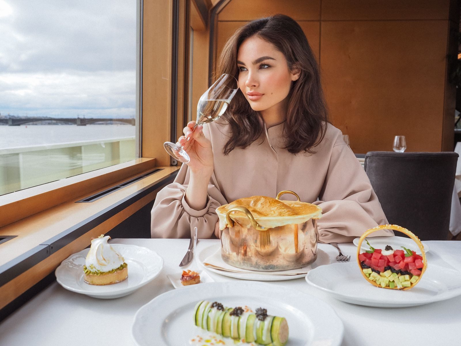 A woman tasting wine over desserts at a window table on a ship, a treat many guests pay for with onboard credit