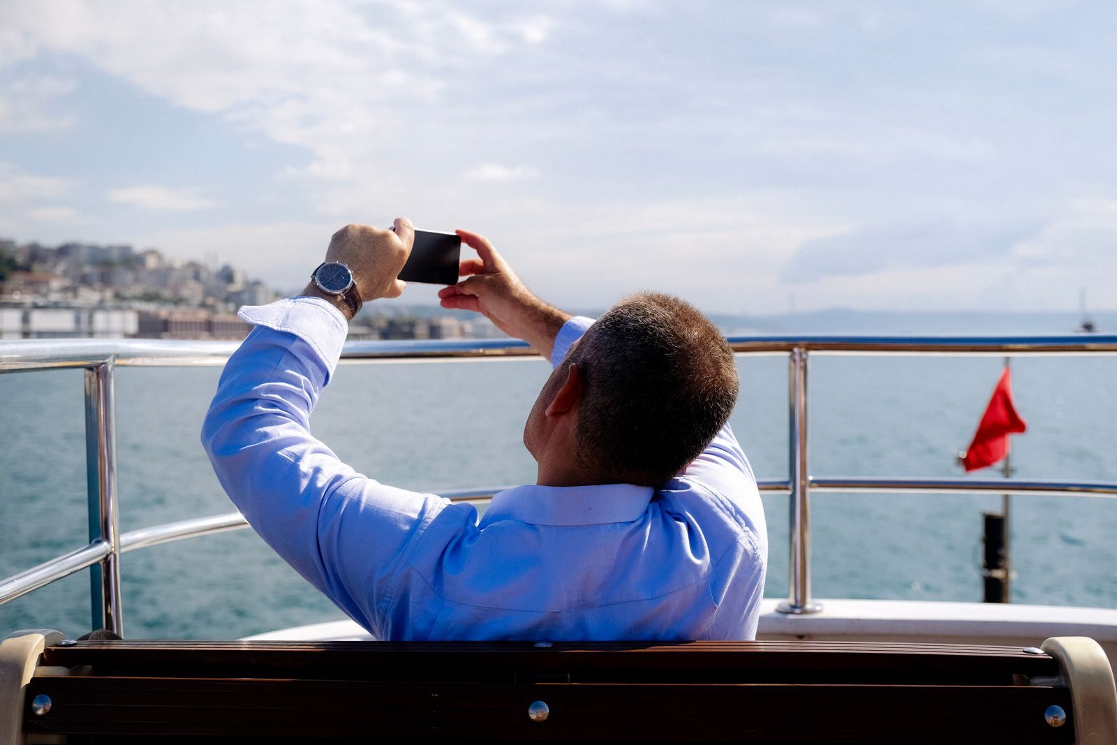 A passenger on a ship&rsquo;s deck photographing the sea with his phone, ready to share it once he has cruise wifi